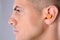 Man wearing foam ear plug on grey background, closeup