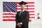 Man wearing a graduate gown and posing in front of USA flag