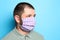 Man wearing handmade cloth mask on blue background, space for text. Personal protective equipment during COVID-19 pandemic