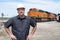 Man wearing hard hat standing in front of train locomotive engine in train yard outside