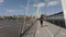 Man wearing headphones walking down the Golden Jubilee Bridge on sunny Sunday morning