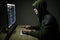 Man wearing hoodie hacking server in dark room. Young man hack server or white hacker protect network