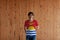 Man wearing Kiribati  flag color of shirt and standing with crossed behind the back hands on the wooden wall background