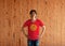 Man wearing Kyrgyzstan flag color shirt and standing with akimbo on the wooden wall background