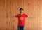 Man wearing Kyrgyzstan flag color shirt and standing with arms wide open on the wooden wall background