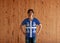 Man wearing Martinique flag color shirt and standing with akimbo on the wooden wall background