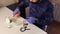 A man wearing a mask and rubber gloves pours orthophosphoric acid into a container. Corroded coins and chemicals for cleaning