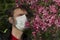 Man wearing a medical mask near blossom tree. Health care concept. Man blurred