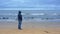 Man wearing navy warm jacket with hood stands on beach sand