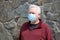 Man wearing a paper mask on his face. A man wears a Medical Face Mask to help avoid contracting Coronavirus aka Covid-19. Covid-19