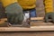 Man wearing protective gloves and using staple gun, fixing wooden objects