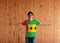 Man wearing Sao Tome and Principe flag color shirt and standing with arms wide open on the wooden wall background