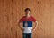 Man wearing Serbia flag color shirt and standing with akimbo on the wooden wall background. A horizontal tricolor of red blue and