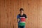 Man wearing South Sudan flag color of shirt and standing with crossed behind the back hands on the wooden wall background