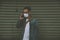 Man wearing surgical mask on street while using phone. Portrait of young man wearing a protective mask to prevent germs, toxic fum