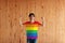Man wearing symbol color of LGBTQ+ shirt and standing with raised both fist on the wooden wall background
