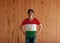 Man wearing Tajikistan flag color shirt and standing with akimbo on the wooden wall background