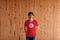 Man wearing Tunisia flag color and standing with crossed behind the back hands on the wooden wall background