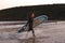 Man Wearing Wetsuit Carrying Surfboard As He Walks Out Of Sea