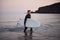 Man Wearing Wetsuit Carrying Surfboard As He Walks Out Of Sea