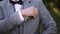 Man with wedding ring in suit and vest and bow tie straightens pockets in jacket