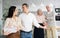 Man welcoming woman home with displeased elderly parents observing