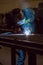 Man welding creating sparks, wearing safety equipment