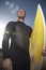 Man In Wetsuit Carrying Surfboard On Beach