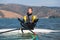 Man in wetsuit sitting on surfing board in lotus position and doing meditation zen exercise. Windsurfing and life balance concept