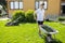 Man with a wheelbarrow of freshly cut grass. Person mows the lawn in the backyardÑŽ