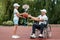 A man in a wheelchair plays basketball with his son on the sports ground. Disabled parent, happy childhood, disabled person