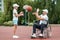 A man in a wheelchair plays basketball with his son on the sports ground. Disabled parent, happy childhood, disabled person