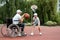 A man in a wheelchair plays basketball with his son on the sports ground. Disabled parent, happy childhood, disabled person