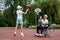 A man in a wheelchair plays basketball with his son on the sports ground. Disabled parent, happy childhood, disabled person