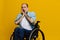 A man in a wheelchair surprised, with tattoos on his arms sits on a yellow studio background, the concept of health is a