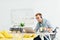 Man in wheelchair using headset, working on laptop and holding cup