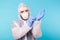 Man in a white decontamination suit putting on medical gloves isolated on blue background. Coronavirus, covid-19 and