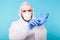 Man in a white decontamination suit putting on medical gloves isolated on blue background. Coronavirus, covid-19 and
