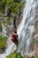 Man with white helmet on its red bacpack looking up at the Dalfazer Waterfall Dalfazer Wasserfall above Achensee, Austria