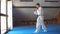 Man in white kimono with black belt training karate in gym