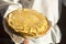 A man in a white national Slavic costume holds a plate of pancakes in his hand. Russian national food. Maslenitsa. Shrovetide