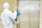 Man in a white protective suit spraying disinfectant in the office building