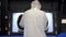 A man in a white protective suit stands near a large 3D printer