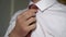 Man in white shirt straightens his brown tie. Young businessman dresses for work