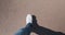 Man in white sneakers and blue jeans walks along an orange path. Top view, pov. The shadow of the feet falls to the