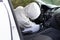 A man in a white sweater with a hood sits at the wheel of a car and tries to start it in order to steal it