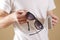 Man in white t shirt hand cleaning black sun glasses lens with i