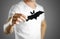 A man in a white t-shirt holds a black silhouette of a bat. Close up