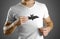 A man in a white t-shirt holds a black silhouette of a bat. Close up