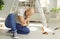 Man who just fell off ladder at home is sitting on floor and touching his hurt elbow